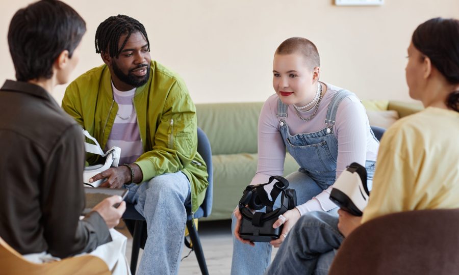 Group of young people having conversation with psychologist while testing VR glasses at session